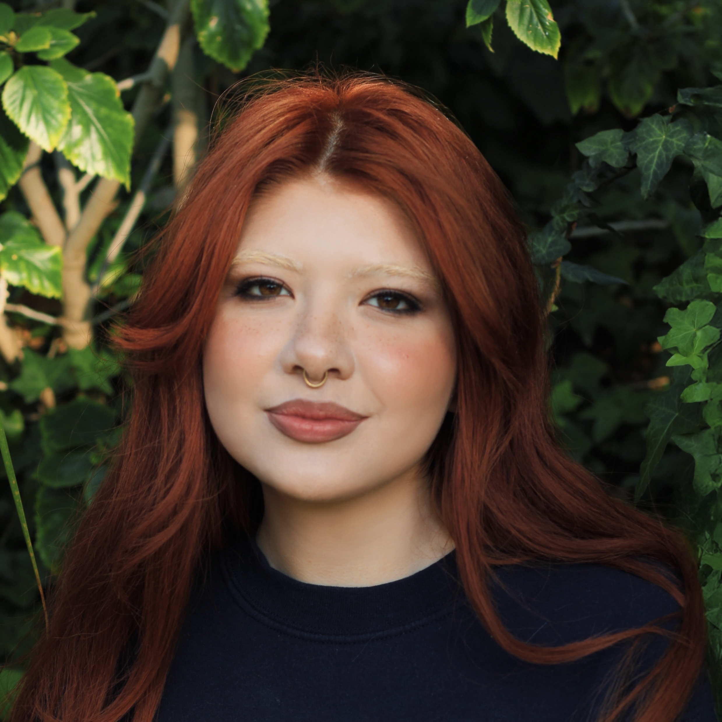 Alumnus Shantay Alvarez posing in front of greenery