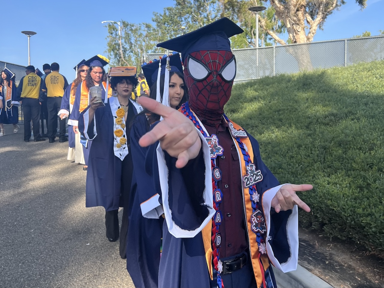 Undergraduate student wearing a Spiderman mask and graduation regalia at Commencement 2025